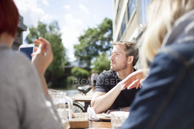 Friends having lunch in cafe by canal — Stock Photo