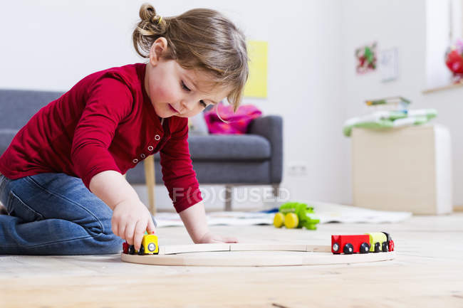 Chica jugando con coches de juguete en casa - foto de stock