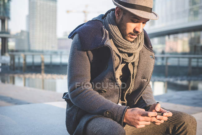 Empresário sentado na parede mensagens de texto no smartphone — Fotografia de Stock