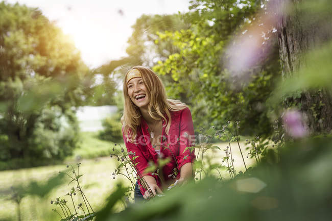 Junge Frau lacht, während sie Blumen im Garten schneidet — Stockfoto