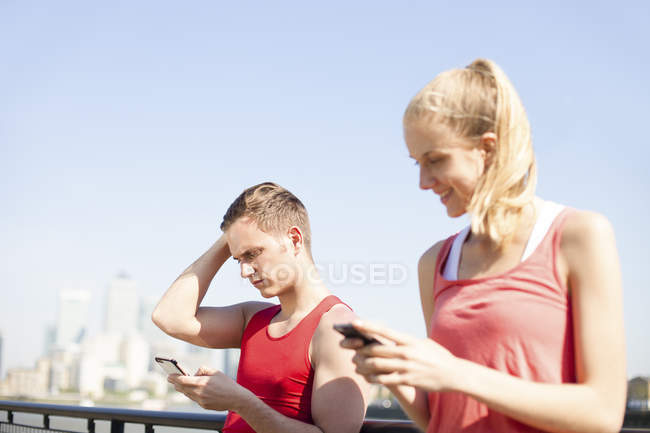 Runners using smartphone on bridge — Stock Photo