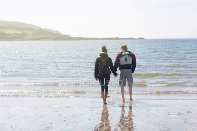 Взрослая пара, держащаяся за руки на пляже, Лох-Эйшорт, остров Скай, Гебриды, Шотландия — стоковое фото