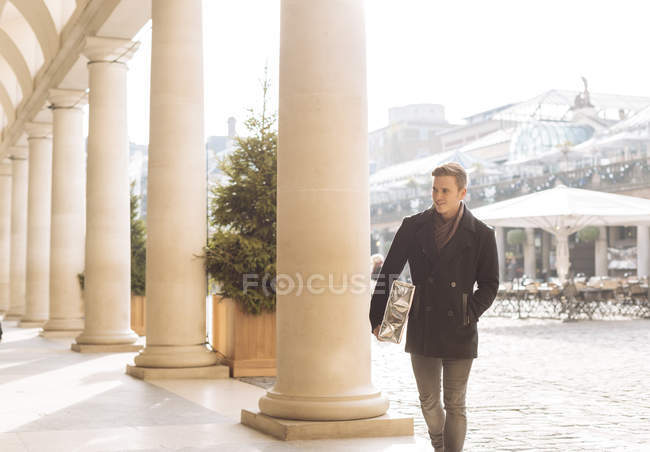 Young man carrying xmas gift in Covent Garden, London, UK — Stock Photo