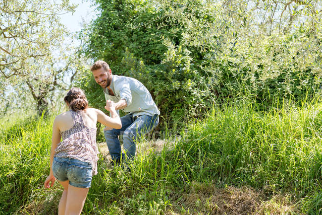 Low angle view of young man helping young woman up hill — Stock Photo