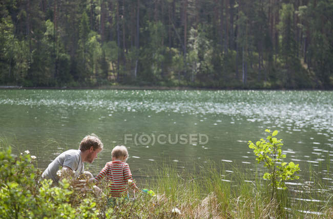Vater und Sohn blicken ins Seewasser, Purzelbaum, Finnland — Stockfoto