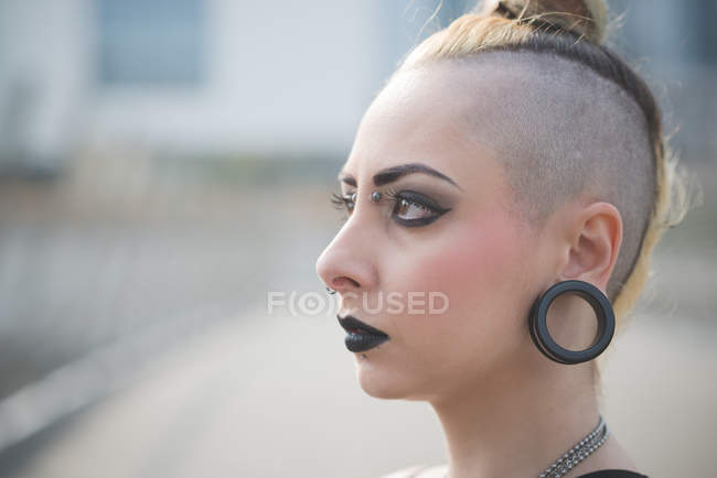 Portrait de jeune punk femelle avec piercing au lobe de l'oreille et tête rasée — Photo de stock
