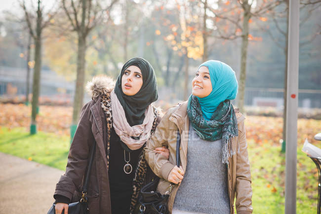 Two young women looking up whilst strolling in park — Stock Photo