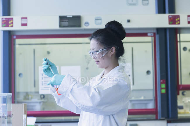 Cientista feminina em amostra de pipetagem de laboratório em copo de laboratório — Fotografia de Stock