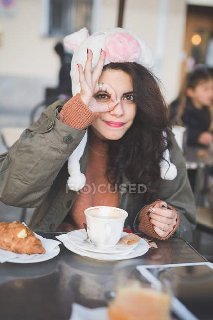 Портрет молодой женщины, делающей нормальный жест рукой в кафе на тротуаре — стоковое фото