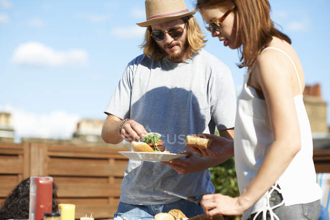Couple eating and talking at rooftop party — Stock Photo