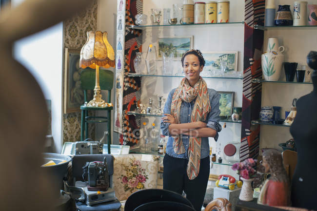 Портрет молодой женщины со сложенными руками в винтажном магазине — стоковое фото