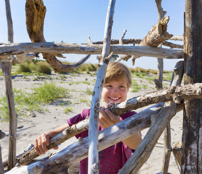 Niño colocando madera a la deriva para construir refugio, Caleri Beach, Veneto, Italia - foto de stock