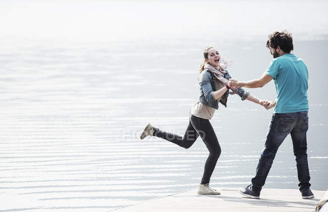 Junges paar, das auf einem steg am mergozzosee herumalbert, verbania, piemont, italien — Stockfoto