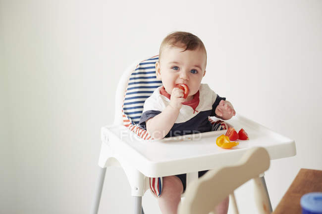 Baby boy eating vegetables in baby chair — Stock Photo