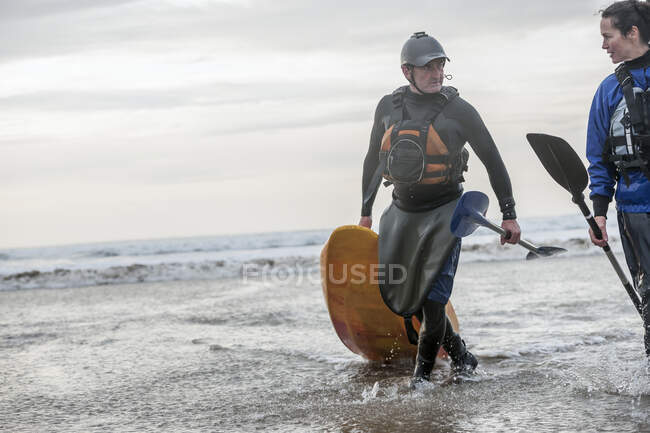 Homme et femme marchant avec kayak de mer — Photo de stock