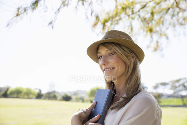 Femme adulte moyenne sur le terrain, tenant le livre — Photo de stock