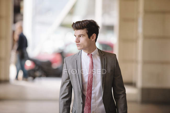 Confident young city businessman walking on sidewalk — Stock Photo