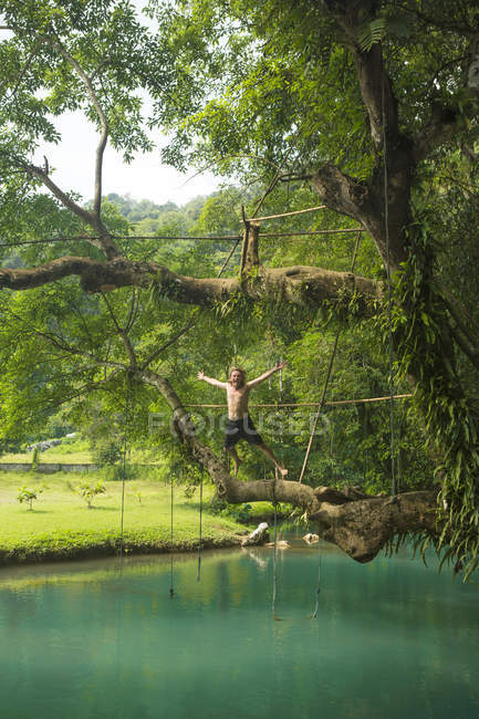 Зрелый человек прыгает в бирюзовую лагуну, Ванг Виенг, Лаос — стоковое фото