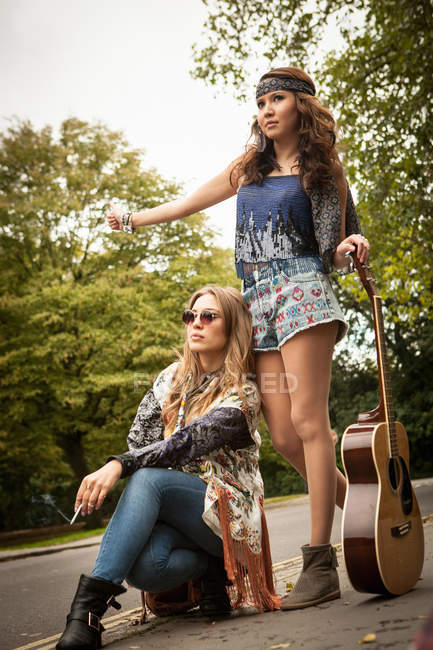 Hippy mujeres jóvenes autoestop-senderismo en carretera del país - foto de stock