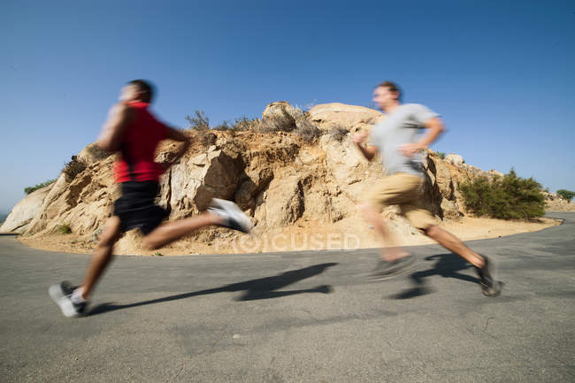 Dos amigos varones, corriendo, al aire libre - foto de stock