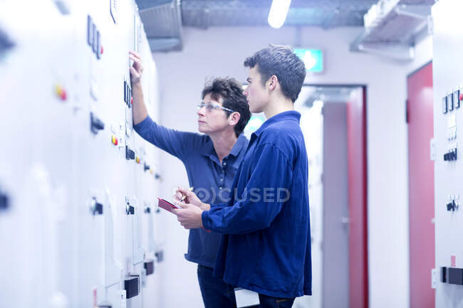 Colleges in control room looking at switchgear — Stock Photo