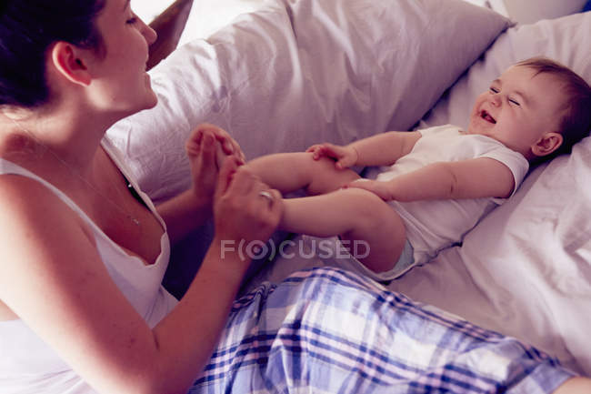 Mère et bébé garçon jouer sur le lit — Photo de stock