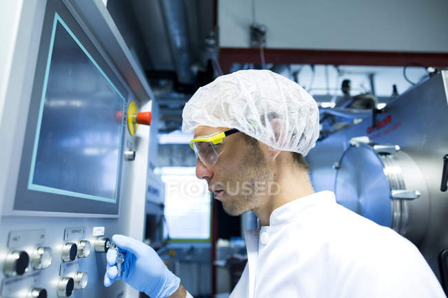 Interruptor de ajuste científico masculino en el panel de control en sala limpia de laboratorio - foto de stock