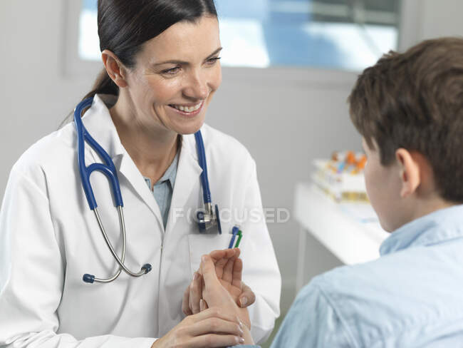 Doctor checking pulse of young boy in clinic — Stock Photo
