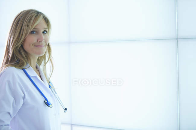 Médico posando contra painel de parede retroiluminado — Fotografia de Stock