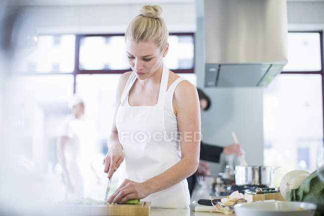 Chef feminino cortando legumes na cozinha comercial — Fotografia de Stock