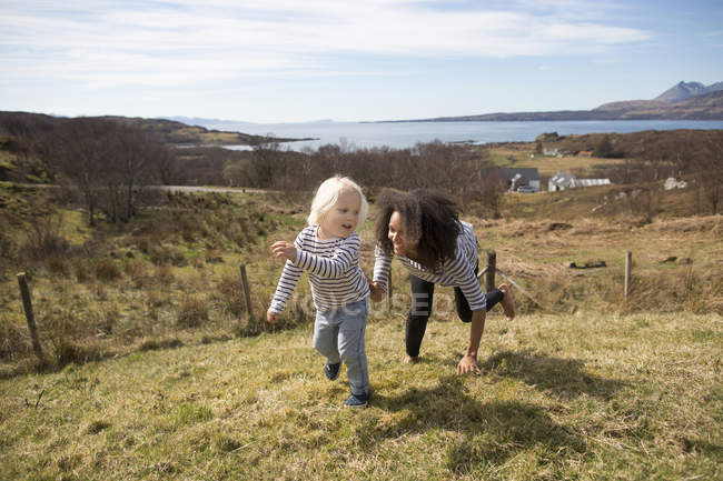 Mother chasing son in field, Isle of Skye, Hebrides, Scotland — Stock Photo