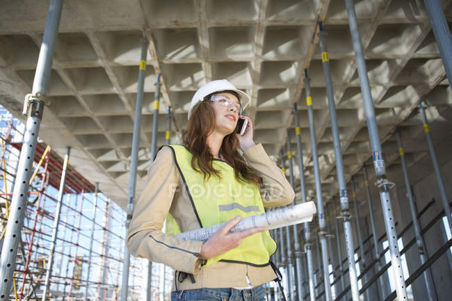 Architect chatting on smartphone on construction site — Stock Photo