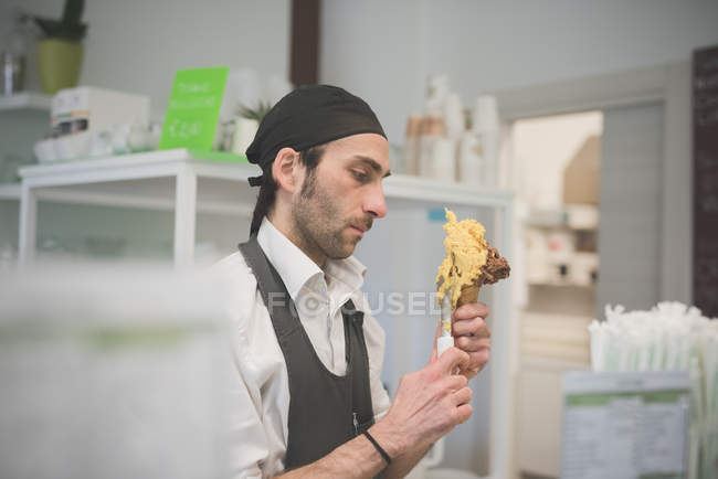 Male waiter serving ice cream cone in cafe — Stock Photo