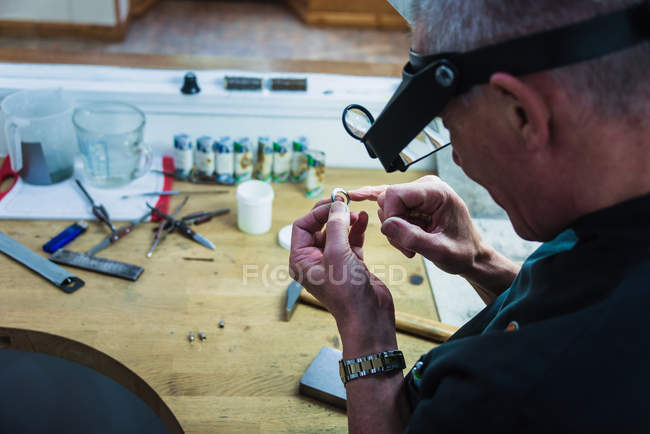 Jewellery craftsman touching platinum ring for smoothness — Stock Photo