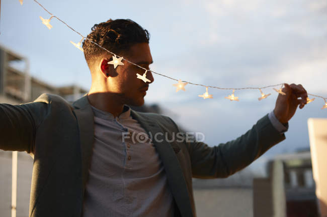 Mann übergibt Gartenlichter für Party am frühen Abend — Stockfoto