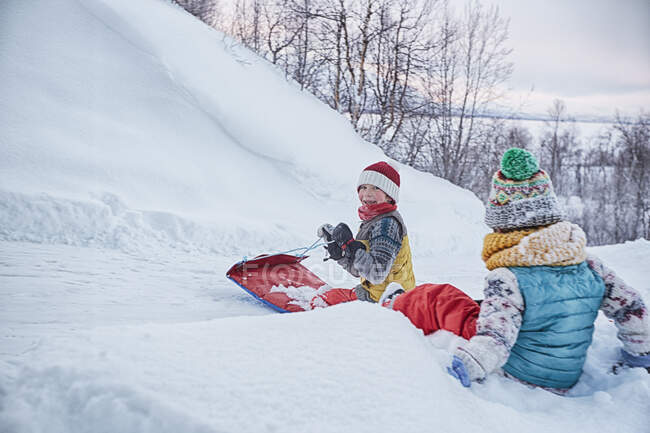 Two brothers on toboggan on snow covered hill, Hemavan,Sweden — Stock Photo