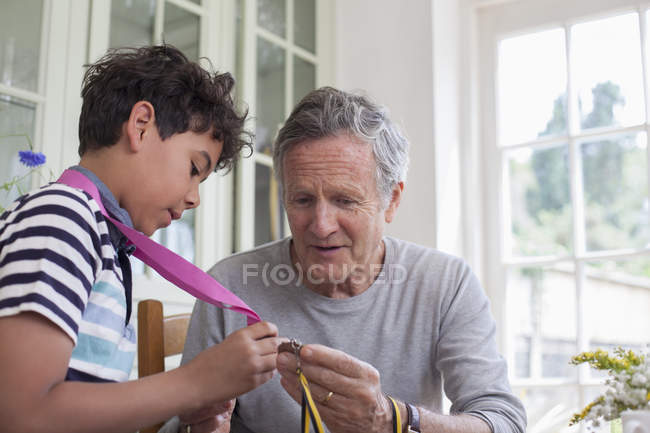 Дедушка и внук смотрят на медали вокруг шеи внука — стоковое фото