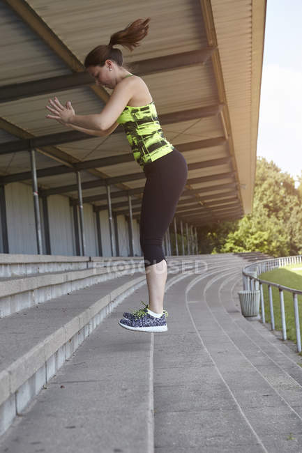 Молода жінка бігун робить тренувальні стрибки на місцях стадіону — стокове фото