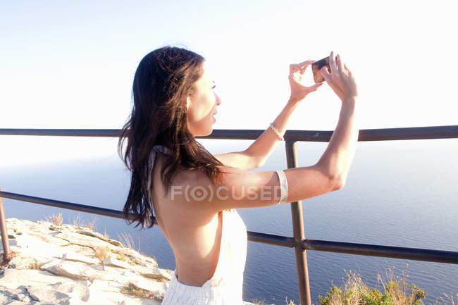 Jeune femme photographiant la mer sur smartphone, Marseille, France — Photo de stock