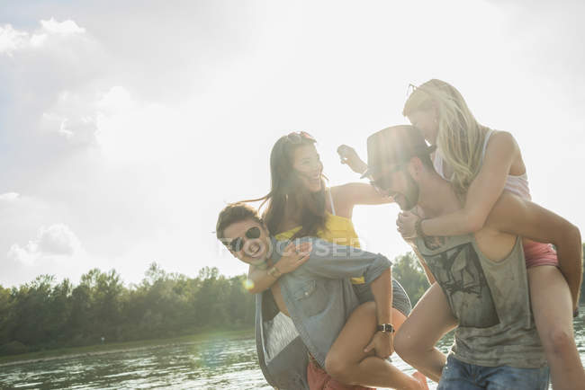 Giovani uomini dando giovani donne schienali piggy — Foto stock