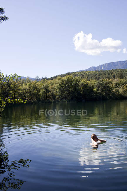 Male hiker swimming in lake, Montiggler Seen, South Tyrol, Italy — Stock Photo