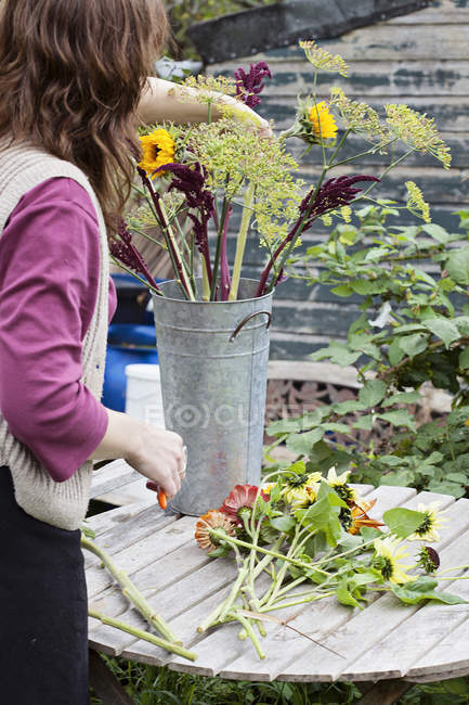 Cropped view of mature woman arranging fresh flowers at allotment — Stock Photo