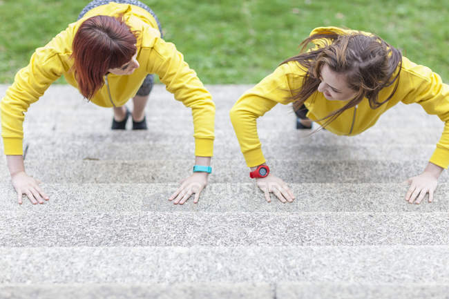 Young women doing push-ups on steps — Stock Photo