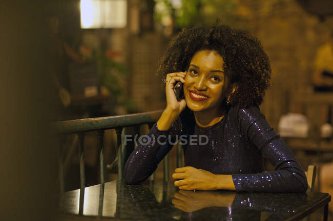 Mujer joven sentada en la mesa en el bar, usando el teléfono móvil - foto de stock