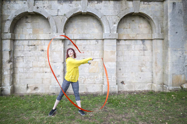 Young woman practising ribbon dance, walled arches in background — Stock Photo