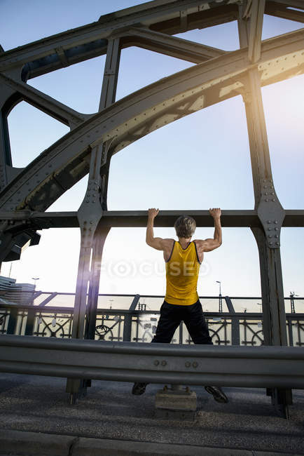 Mann macht Klimmzüge auf Brücke, München, Bayern, Deutschland — Stockfoto