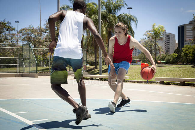 Молоді чоловіки грають у баскетбол на баскетбольному майданчику. — стокове фото