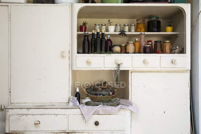 Jars and bottles of home-made food on retro style kitchen cabinet — Stock Photo