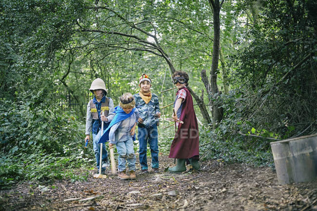 Cuatro chicos vestidos y jugando en el bosque - foto de stock