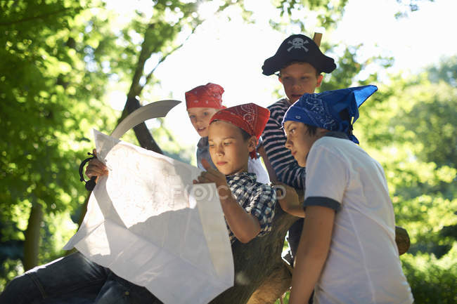 Pré-adolescents habillés en pirates lisant la carte — Photo de stock